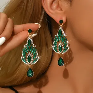 Dettaglio di lunghi orecchini pendenti con lussuosi cristalli strass verdi, gioielli da sposa.