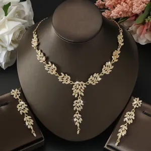 Dettaglio del set di collana e orecchini da sposa con foglie dorate e strass brillanti.