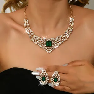 Close up of luxury vintage crystal rhinestone necklace and earrings set with green gem.
