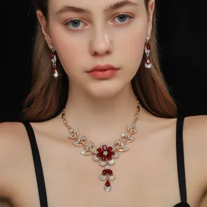 Primo piano dettagliato di collana floreale dorata e orecchini abbinati con pietre rosse.