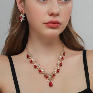 Completo di gioielli dorati con strass rossi, collana e orecchini eleganti da donna.
