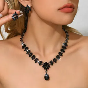 Dettaglio in primo piano di collana e orecchini in cristallo nero con foglie per abiti da sera.