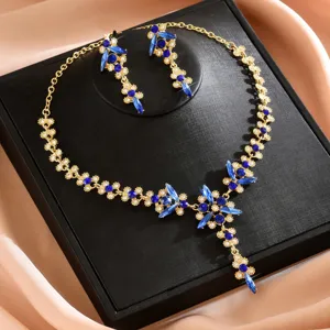 Primer plano detallado de un conjunto de joyas dorado con cristales azules y motivos de hojas.
