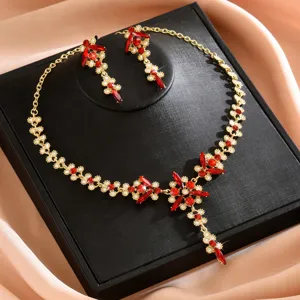 Detalle en primer plano del collar de novia dorado con cristales rojos y pendientes.