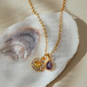 Exquisite gold necklace with yellow flower and purple teardrop zircon pendants, detailed shot.