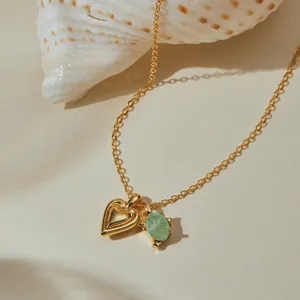 Detail shot of the gold-plated heart and green gemstone pendant necklace close up view.