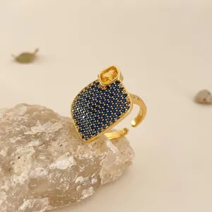 Detalle de anillo de circonita cuadrada geométrica con piedras azules y amarillas dorado.