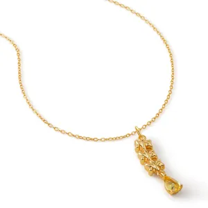 Detalle del collar dorado con colgante de ositos y piedra de circonita amarilla.