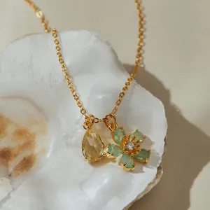 Close-up detail view of the dainty gold-plated necklace with teardrop and flower charms.