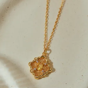 Primer plano detallado del exquisito collar con colgante floral tallado hueco y piedra amarilla.