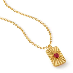 Détail de collier plaqué or avec pendentif rectangulaire rayonnant et pierre cœur rouge.