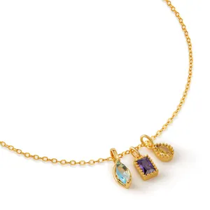 Detailed view of dainty gold chain necklace with multi-color zircon charms, delicate jewelry close-up.
