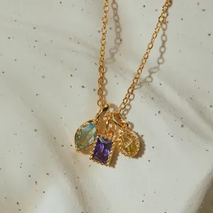 Detailed close-up view of a gold-plated necklace featuring three multi-colored cubic zirconia charms.