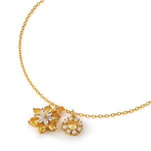 Detailed view of gold chain necklace featuring dual floral pendants with sparkling zircon stones.