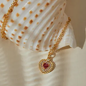 Détail exquis d'un collier de rubis en forme de cœur avec zircons et chaîne dorée.