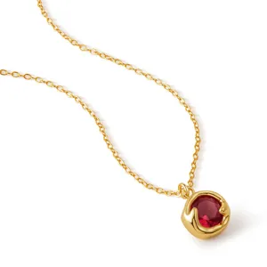 Gros plan détaillé du pendentif en pierre rouge et de la chaîne dorée, bijou élégant.