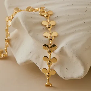 Primer plano de una pulsera de abalorios de trébol geométrico chapado en oro con circón.