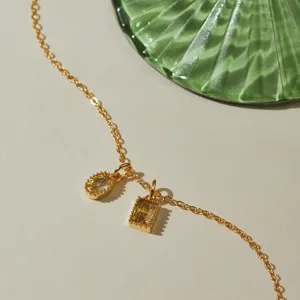 Close-up detail of a gold-toned necklace featuring oval and rectangular yellow zircon charms.