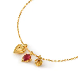 Close-up detail shot of a delicate gold chain necklace featuring heart and gemstone pendants.