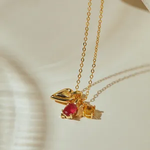 Close-up of a gold-tone necklace featuring heart and multi-color gemstone pendants.