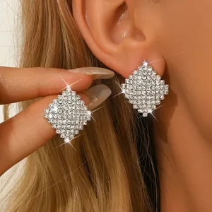 Dettaglio orecchini a lobo rombo strass scintillanti, design cristallo geometrico chic.