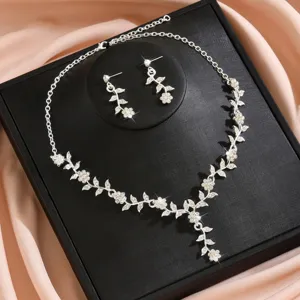 Detalle de conjunto de collar y pendientes de aleación con pedrería floral para novia boda.
