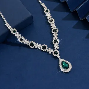 Close-up shot of elegant silver necklace with teardrop green crystal pendant and rhinestones.