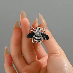 Primo piano dettagliato di una simpatica spilla ad ape in strass con ali in smalto nero.