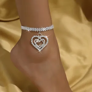 Close-up detail of a sparkling rhinestone anklet with a double heart pendant on ankle.