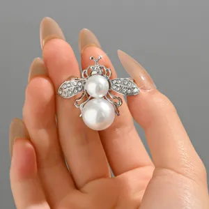 Dettaglio ravvicinato di una delicata spilla ad ape con eleganti perle e brillanti strass.