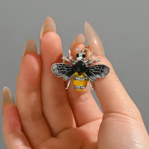 Primo piano dettagliato di una spilla ape in cristallo con smalto giallo e strass scintillanti.