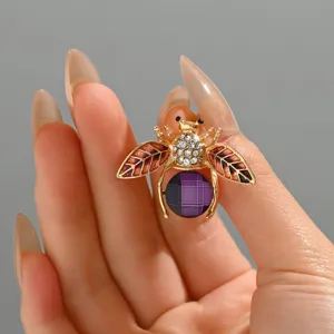 Elegante spilla a forma di ape dorata con strass scintillanti e addome in cristallo viola.