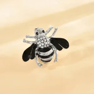 Primo piano dettagliato di una spilla ape argentata con strass e smalto nero lucido.