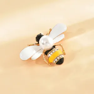 Primo piano della spilla ad ape elegante con ali in smalto bianco e strass brillanti.