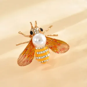Primo piano dettagliato di una spilla a forma di ape dorata con strass e perla.