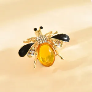 Primo piano dettagliato di un'elegante spilla ad ape in strass con corpo ambrato e ali nere.