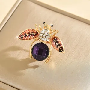Dettaglio ravvicinato della spilla ad ape con pietra viola e strass splendenti e luminosi.