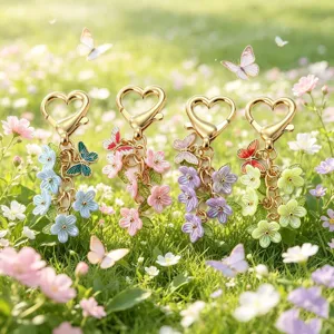 Detailansicht von vier bunten Emailleschmetterlings Blumen Schlüsselanhänger auf grünem Gras.