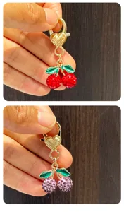 Rhinestone cherry keychain detail close up, sparkling crystal fruit with gold heart clasp.