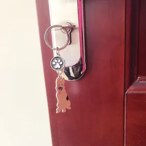 Detail shot of a cute metal German Shepherd dog keychain with paw charm hanging on a door.