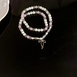 Zartes doppellagiges Perlenarmband mit rosa Kristallen und silberner Schleifen-Anhänger.