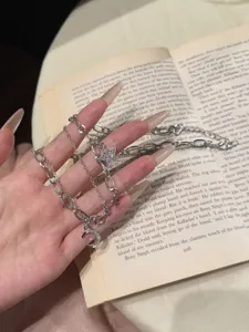 Detail shot of a silver multi-layer necklace with star and moon charms on a book background.