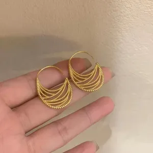 Nahaufnahme im Detail von koreanischen minimalistischen goldenen Creolen mit Lochmuster.