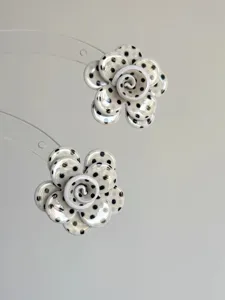 Nahaufnahme von schwarz-weißen Pünktchen-Blumenohrringen mit einzigartigem Lagen-Design.