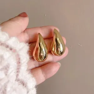 Nahaufnahme glänzender goldener Tropfenohrringe mit glatter Metallstruktur und edlem Design.