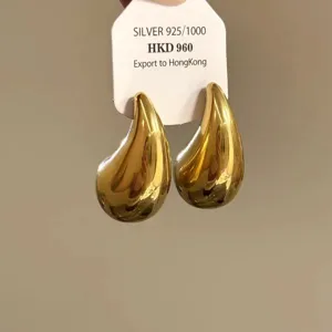 Goldene Tropfen Ohrringe in Detailansicht, minimalistisches glattes Metall Design.
