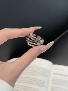 Primer plano del anillo de plata entrelazado multicapa con grabado FOREVER, diseño abierto.