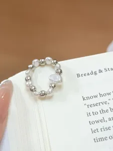 Close-up detail of pearl and silver bead elastic ring, elegant everyday jewelry piece.