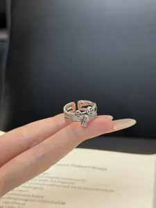 Anillo abierto de plata en detalle, con bonitos dijes de moneda y maní para un estilo muy trendy.