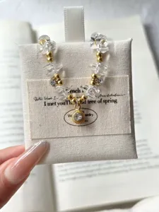 Klares Quarz-Perlenarmband mit goldenen Kugeln und funkelndem Strass-Anhänger im Detailansicht.